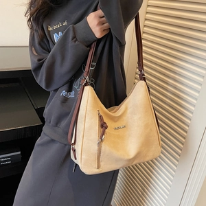Large beige hobo shoulder bag with brown straps and side zipper shown on model