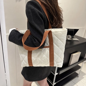 Quilted beige puffer tote bag with brown straps shown on shoulder for daily commute
