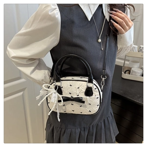 Close-up of white crossbody bag with black bow details, pearl charms, and lace trim