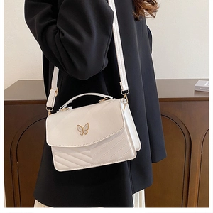 Close-up of white quilted PU leather crossbody bag featuring gold butterfly metal decor