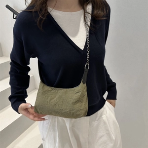 Minimalist olive green wrinkled nylon crossbody bag with silver chain strap worn by a model