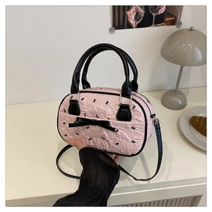 Pink bowling bag with black bow accents and wrinkled texture on a cozy table setting