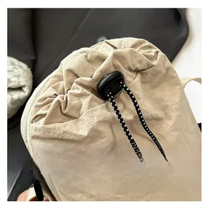 Détail du sac de téléphone beige en nylon plissé avec fermeture à cordon et boucle noire