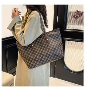 Detail of vintage checkerboard tote bag with monogram print and long brown leather handles