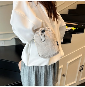 Détail du sac bandoulière beige à cordon en nylon texturé avec étiquette de mode noire