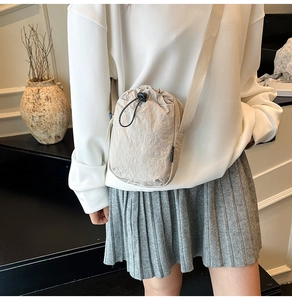 Détail d'un mini sac bandoulière en nylon beige avec cordon de serrage et sangle réglable