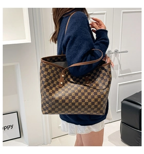 Detail of checkered tote bag showing leather strap and golden rivet reinforcement