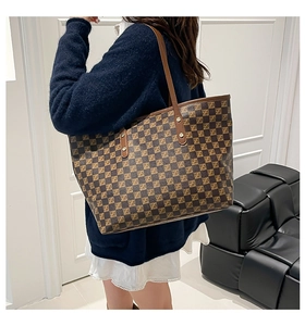 Detail of classic brown checkered tote bag with geometric symbols on leather shoulder strap