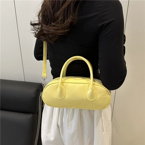 Light yellow patent leather bowling bag with top handles shown on model's shoulder