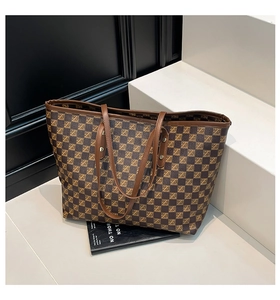 Close-up of vintage tote bag with checkerboard pattern and brown leather handles