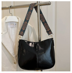 Detail of glossy black hobo bag with a colorful ethnic jacquard woven shoulder strap