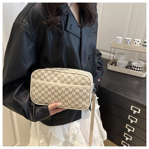 Détail du sac bandoulière avec motif M gris et poche zippée sur le devant