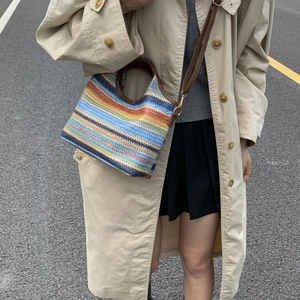 Sac seau en paille à rayures arc-en-ciel avec poignées en cuir et trench-coat kaki chic