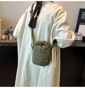 Mini sac à bandoulière en nylon vert armée avec cordon de serrage, porté par un mannequin