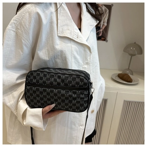 Gros plan sur un sac bandoulière noir avec motifs M gris et finitions métalliques argent