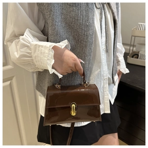 Détail d'un sac à main en cuir verni marron brillant avec fermoir en métal doré de style chic