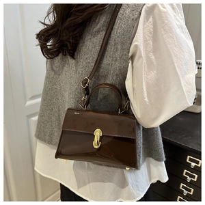 Détail d'un sac à main en cuir verni marron foncé avec fermoir doré en intérieur