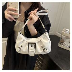 Close-up of white leather crescent bag with silver buckles and stud details