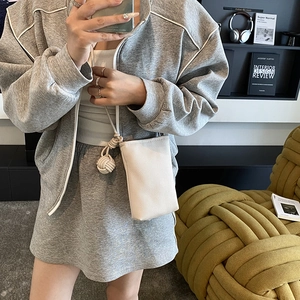 Minimalist off-white lychee texture bucket bag with side rope knot worn by a model