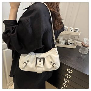 Detail of white PU leather crescent bag with decorative metal buckles and Y2K aesthetic