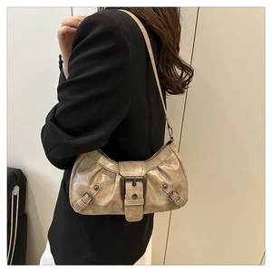 Detail of light brown hobo bag with vintage metal buckle and pleated leather texture