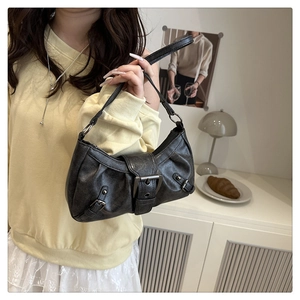 Close-up of black vintage texture leather underarm bag with silver buckle and pleats