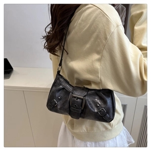 Close-up of vintage black distressed leather underarm bag with Y2K metal buckle details