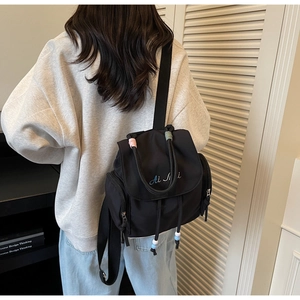 Dettaglio dello zaino in nylon nero con chiusura a coulisse e perline colorate
