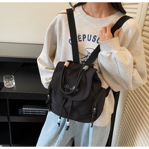Detail of mini black nylon backpack with Ai Mi embroidery and colorful woven handle