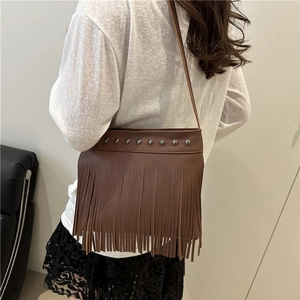 Sac fourre-tout en cuir marron avec glands bohèmes et rivets métalliques, porté épaule