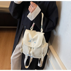 Dettaglio dello zaino in tela bianco sporco con ricamo, coulisse e tasche laterali