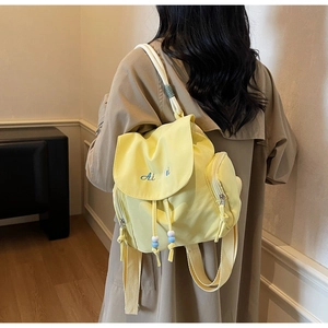 Dettaglio di uno zaino in nylon giallo con logo ricamato, coulisse e perline colorate