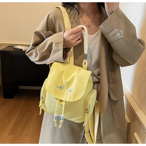 Dettaglio di zaino in nylon giallo con ricamo blu e chiusura a coulisse