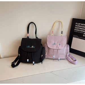 Dettaglio di mini zaini alla moda neri e lilla con manici intrecciati e ricami fini