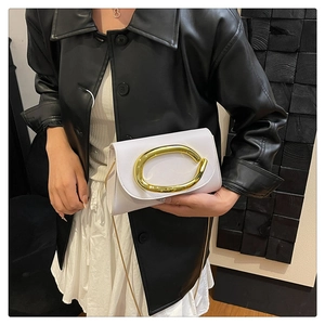 Détail du sac bandoulière en similicuir blanc avec boucle ovale dorée et chaîne fine