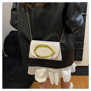 Détail du petit sac bandoulière blanc crème avec boucle dorée porté par un mannequin