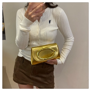 Détail de la pochette dorée brillante avec une grande boucle ovale et une bandoulière