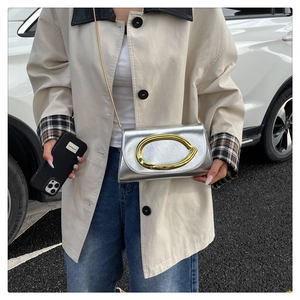 Détail d'un sac bandoulière en cuir argenté avec une grande boucle en métal doré