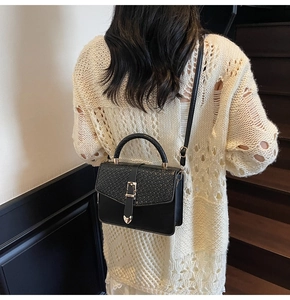 Détail du sac à bandoulière noir aspect crocodile avec fermoir doré élégant