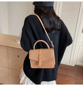 Detail of light brown woven texture crossbody bag with elegant gold triangle metal clasp