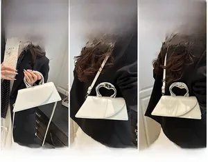 Detail of white asymmetric leather crossbody bag with unique silver metallic handle