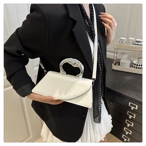 Dettaglio borsa a trapezio in pelle bianca con manico in metallo argento e tracolla elegante