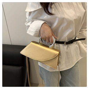 Borsa a trapezio color champagne con manico metallico indossata da una modella