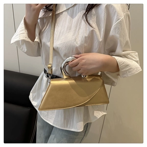 Borsa a trapezio dorata con manico in metallo argentato indossata da una modella