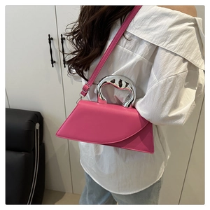 Detail of fuchsia geometric handbag with chunky silver metal handle worn by a model