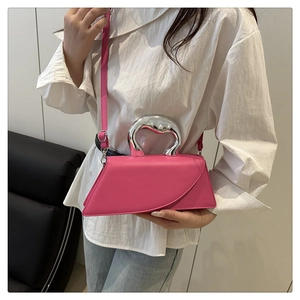 Dettaglio borsa asimmetrica fucsia con manico in metallo argento su abito bianco