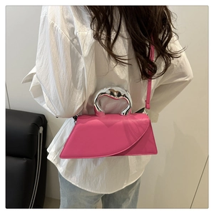 Dettaglio della borsa rosa con manico scultoreo in argento e design asimmetrico moderno