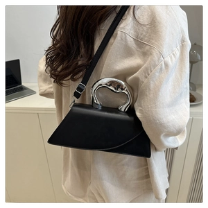 Detail of black geometric bag with unique silver metallic handle and smooth leather texture