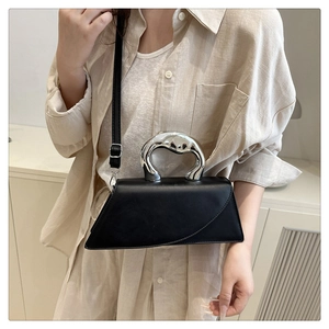 Detailed shot of asymmetrical matte black handbag featuring a silver organic liquid handle