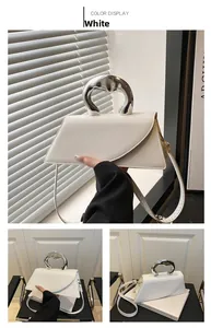 Dettaglio della borsa bianca geometrica con manico in metallo argento e design a busta
